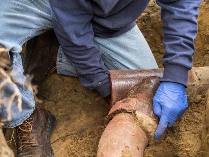 Man Digging Out Clogged Sewer Line Closeup